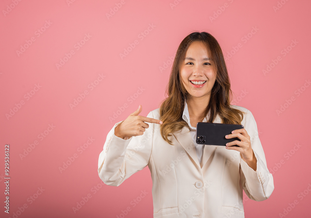 Portrait Asian happy beautiful young woman smile making finger pointing on screen smartphone in hand, female attractive shopping online application isolated studio shot pink background with copy space Portrait Asian happy beautiful young woman smile making finger pointing on screen smartphone in hand, female attractive shopping online application isolated studio shot pink background with copy space