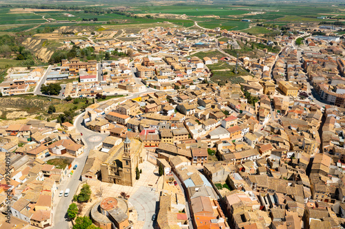 Scenic drone view of Ejea de los Caballeros townscape with baroque bell tower of Church of Santa Maria rising above terracotta tiled roofs of houses on spring day, Spain photo