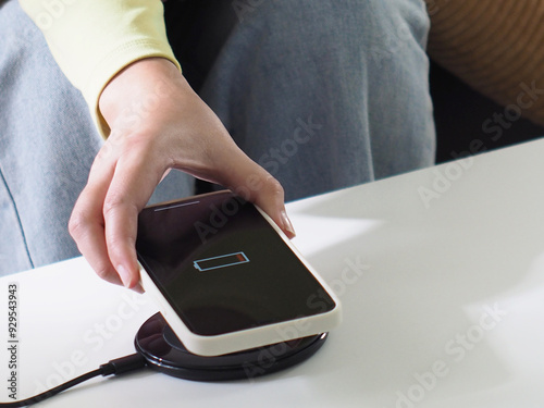 Charging mobile phone battery with wireless charging device in the table. Smartphone charging on a charging pad. Mobile phone near wireless charging
