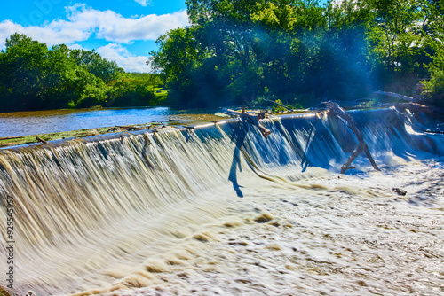 Waterfall Over Weir with Tree Debris in Lush Forest Low Perspective