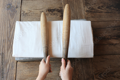 Wolmido Island, Jung-gu, Incheon, South Korea - April 15, 2022: Top angle view of female hands holding two fulling mallets on white cloth and fulling stone at Yangjindang House of Wolmido Park photo