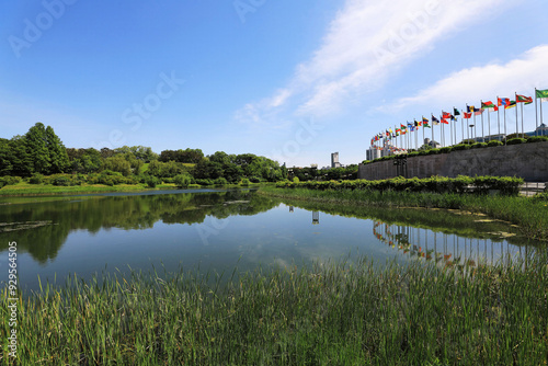 Olympic Park, Songpa-gu, Seoul, South Korea - May 9, 2022: Summer view of Mongchon Lake with national flags at Pyeonghwa Plaza photo