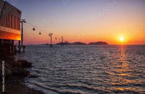 Jeongok Port, Hwaseong-si, Gyeonggi-do, South Korea - March 2, 2022: Sunset view of terminal of Jebudo Marine Cable Car with cablecars moving over the sea against Jebudo Island and horizon photo