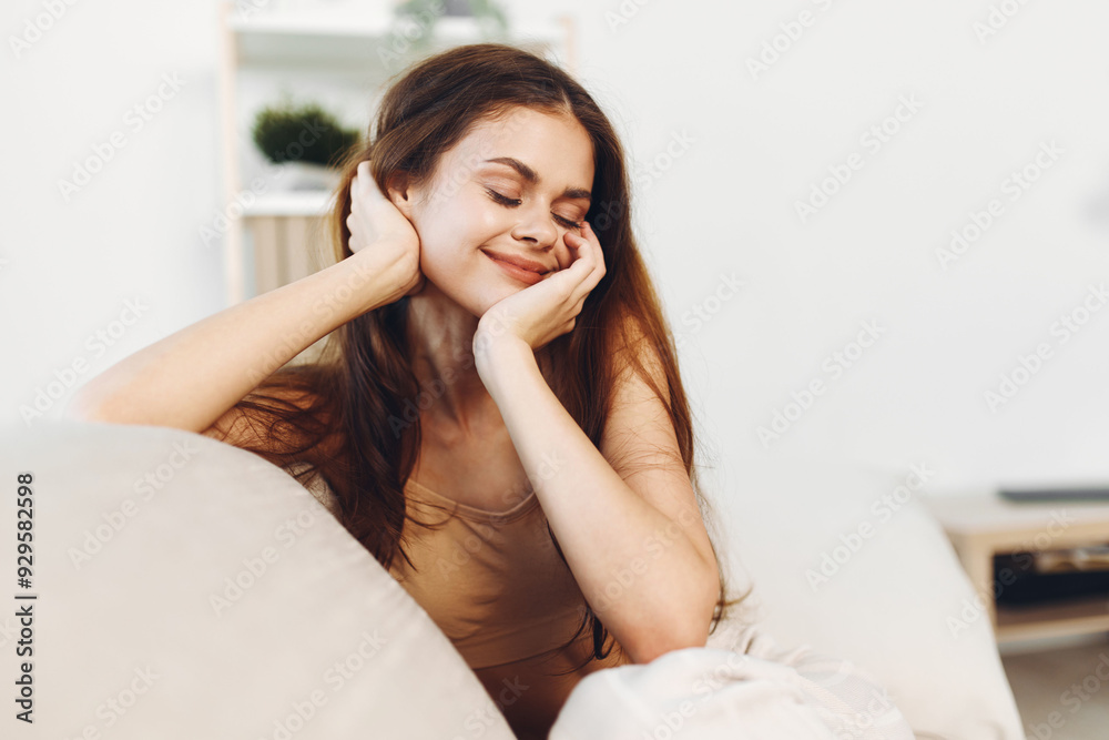 Happy Woman Smiling, Relaxing on a Cosy Couch in a Modern White Living Room