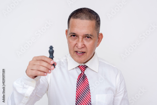 An astute but ruthless manager and professional middle aged man holding a king chess piece. Checkmate victory alluding him being the mastermind of a business win. Isolated on a white backdrop.