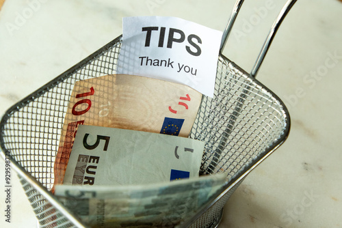 Euro bank notes in a wire container as tips after a meal in a restaurant.