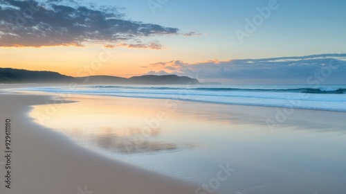 A serene beach at sunrise, showcasing soft waves and a colorful sky.