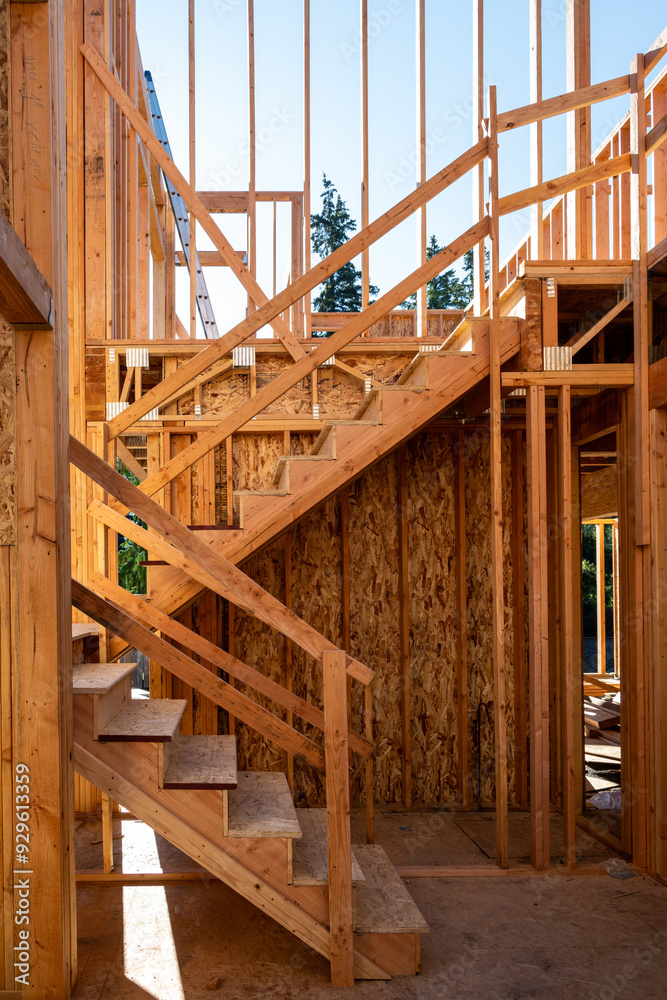 Summer construction season, two story new house build in progress at the framing stage, interior wood staircase on sunny morning
Summer construction season, two story new house build in progress at the framing stage, interior wood staircase on sunny morning
