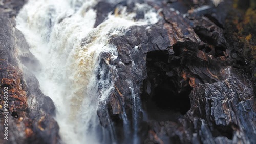 A raging waterfall cascades over the jagged cliffs, with the natural landscape adding to the dramatic effect. A tilt-shift video. photo