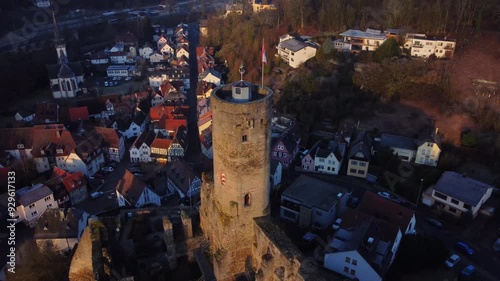 Drone footage of Eppstein Castle and medieval old town in Germany at sunrise. The serene morning light highlights historic architecture of castle and medieval town of Europe. Shots: Fly Back photo