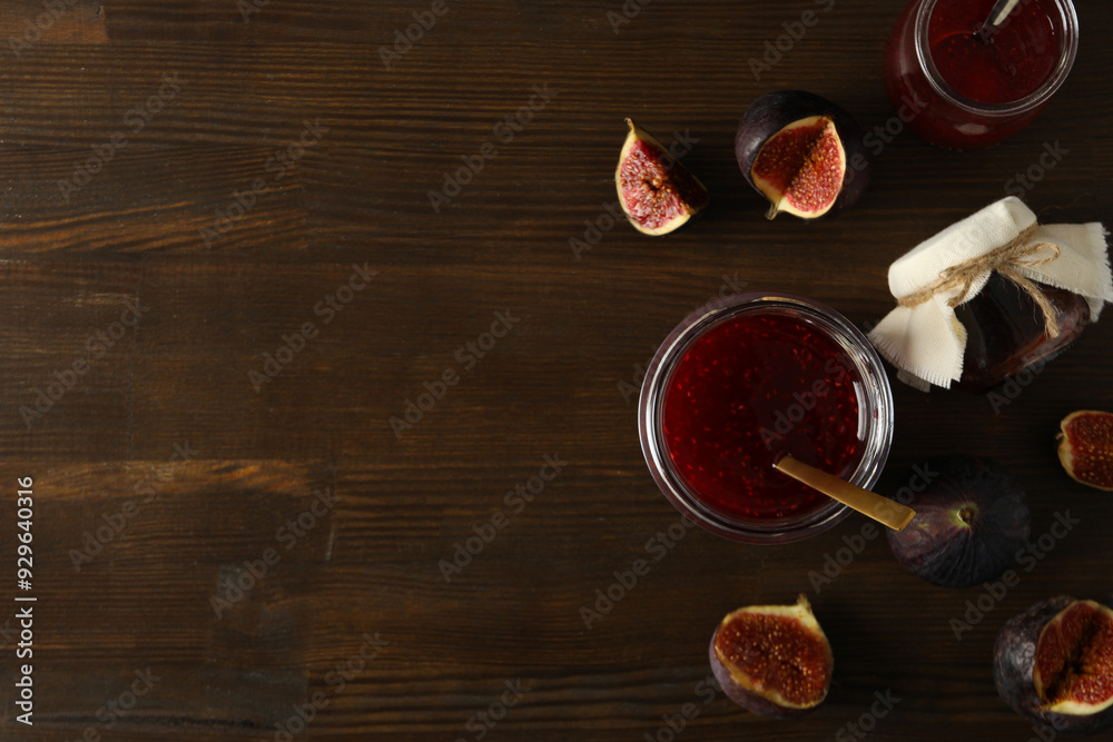 Glass jars with fig jam, spoon and cut figs on wooden background, space for text Glass jars with fig jam, spoon and cut figs on wooden background, space for text
