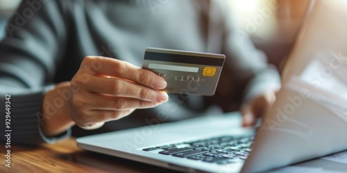 Hands holding plastic credit card and using laptop