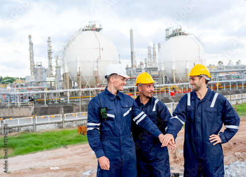 Factory engineer or technician workers stand and join hands together in front of tank of refining and petrochemical factory with day light.