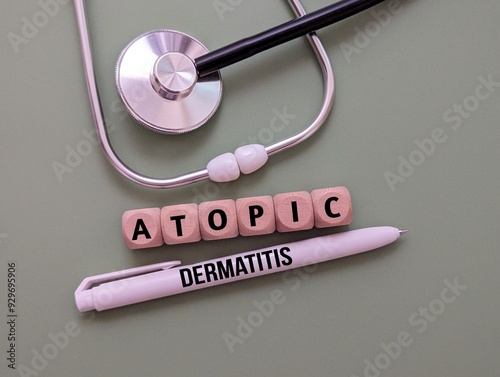 Stethoscope, word atopic dermatitis on wooden cube and pen. the concept of illness