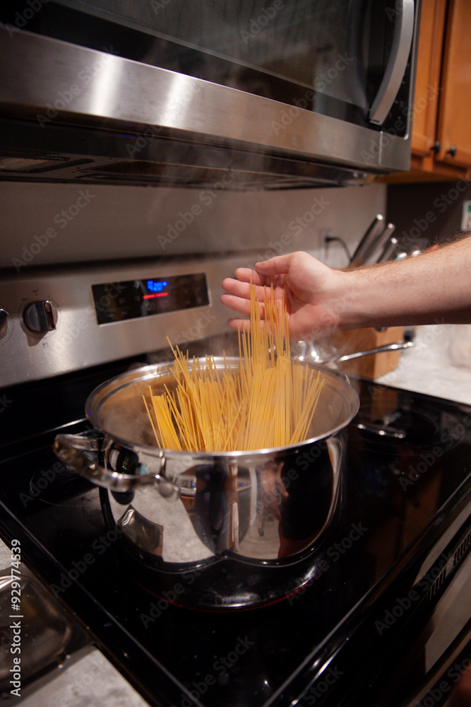 Uncooked spaghetti going into a pot of boiling water on the stove Uncooked spaghetti going into a pot of boiling water on the stove