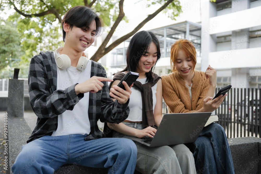 Three young asian people happily using technology outdoors, connecting with friends and the community through smartphones and laptops, embodying togetherness and youth in the digital age Three young asian people happily using technology outdoors, connecting with friends and the community through smartphones and laptops, embodying togetherness and youth in the digital age