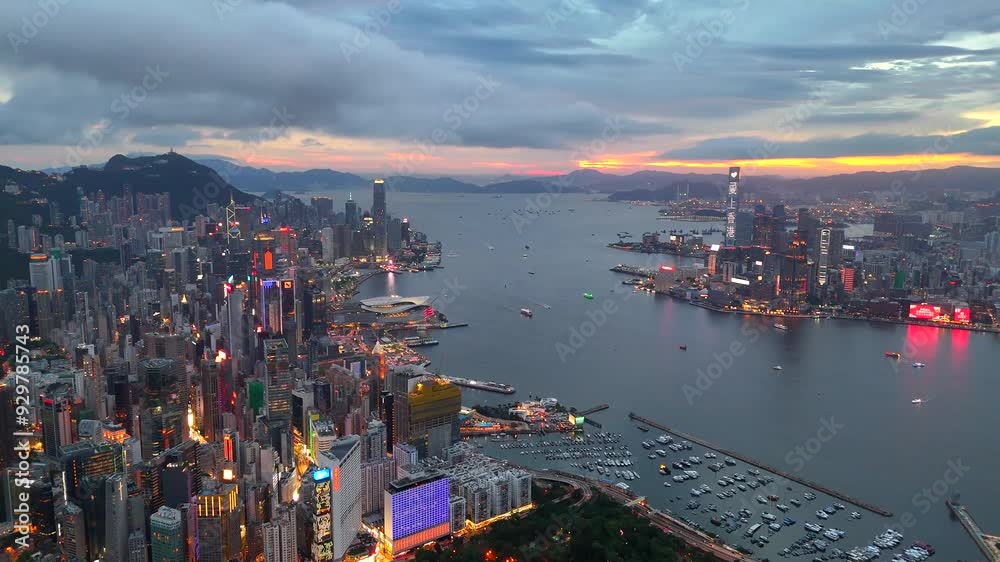 Aerial view drone video City landscape of the famous travel landmark cityscape. buildings with light and transportation at Victoria Harbour skyline and Kowloon at sunset along Hong Kong Island China.