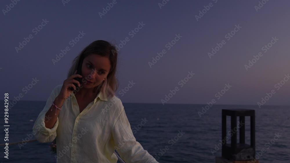 A woman is speaking by phone at the beach. A woman is speaking by phone at the beach.