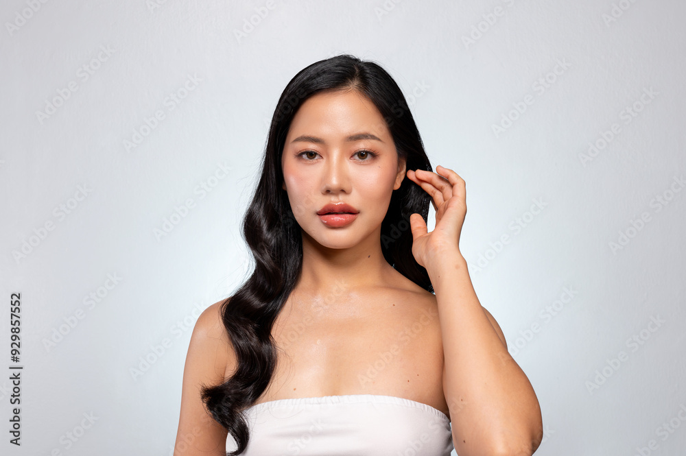 Beautiful Asian woman with healthy black curly hair and tanned skin poses against a grey background. Beautiful Asian woman with healthy black curly hair and tanned skin poses against a grey background.