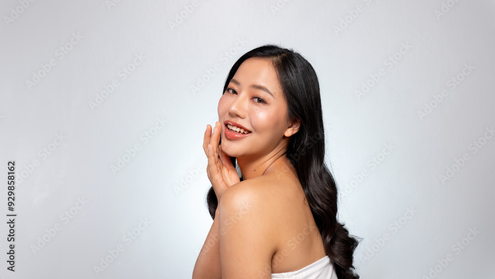 An Asian beauty model with glowing tanned skin and long black hair poses against a grey background. An Asian beauty model with glowing tanned skin and long black hair poses against a grey background.