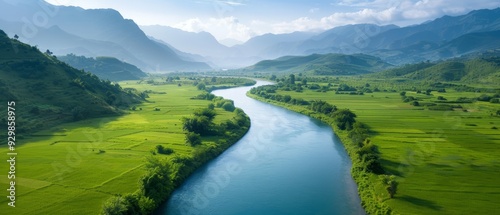  A river runs through a verdant valley, bordered by mountains, where lush green grass covers the landscape