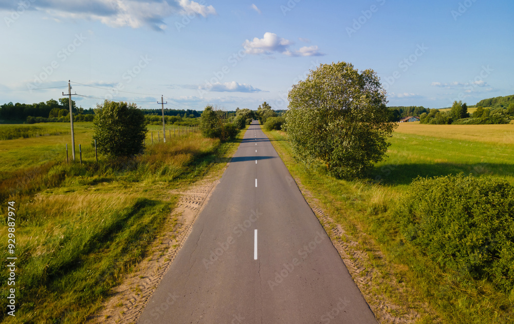 Fototapeta premium Drone view of the highway road, forest and fields, top view and blue sky
