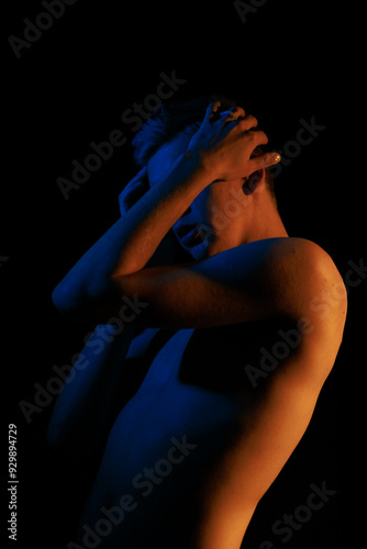 Young man posing in the dark with red and blue light in the studio