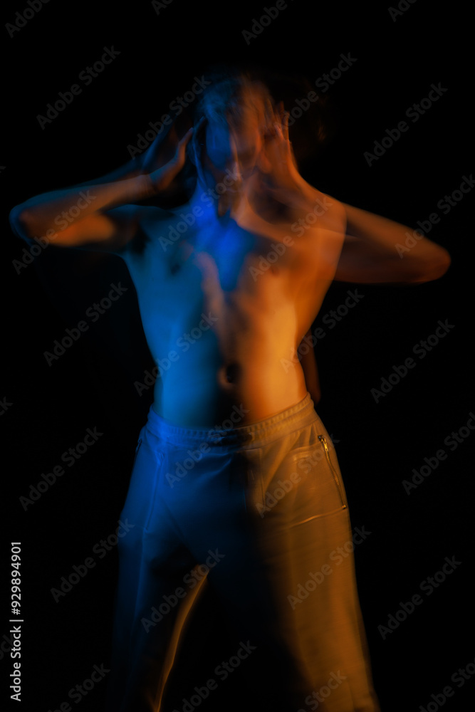 blurred silhouette, young man posing in the dark with red and blue light in the studio blurred silhouette, young man posing in the dark with red and blue light in the studio