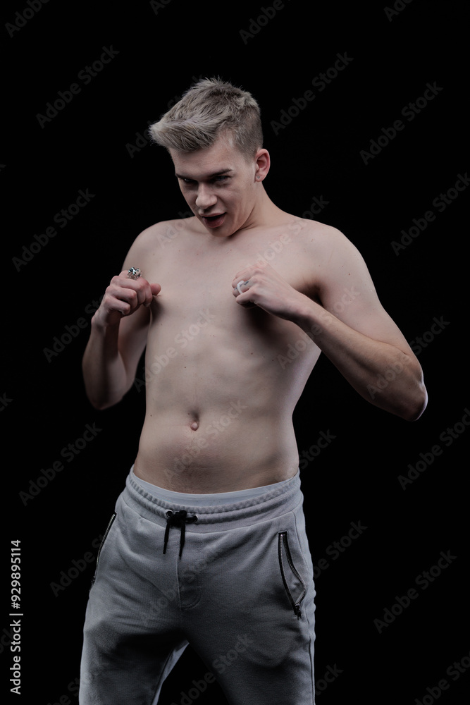 Fototapeta premium Young man posing in the dark in the studio