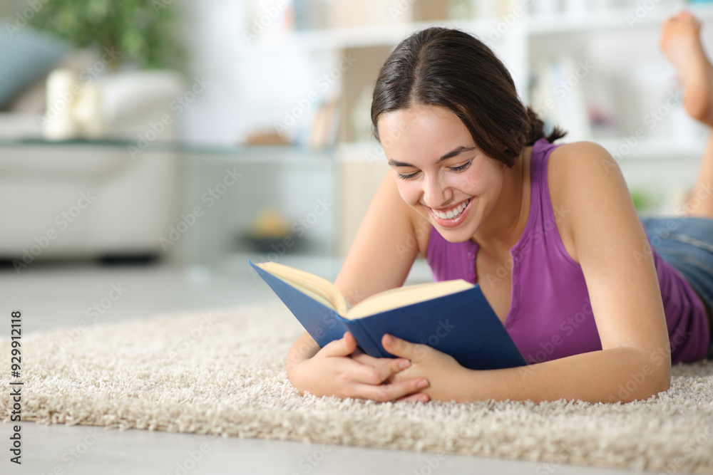 Fototapeta premium Happy woman reading a paper book on the floor at home