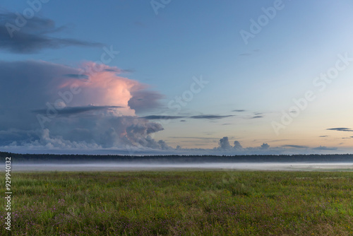 A large cloud is in the sky and the sun is setting