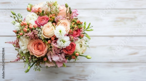 Wedding bouquet viewed from above, placed on a wooden surface, with a clean white background for contrast.