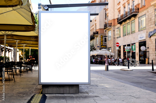 bus shelter at busstop. white poster ad display space and lightbox. mockup template. blank ad panel. glass design. urban street setting. soft background. silhouettes in a distance