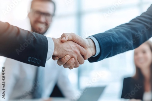 Businessmen shaking hands in the office with blurred background, close-up of handshake and smiling people at a table.