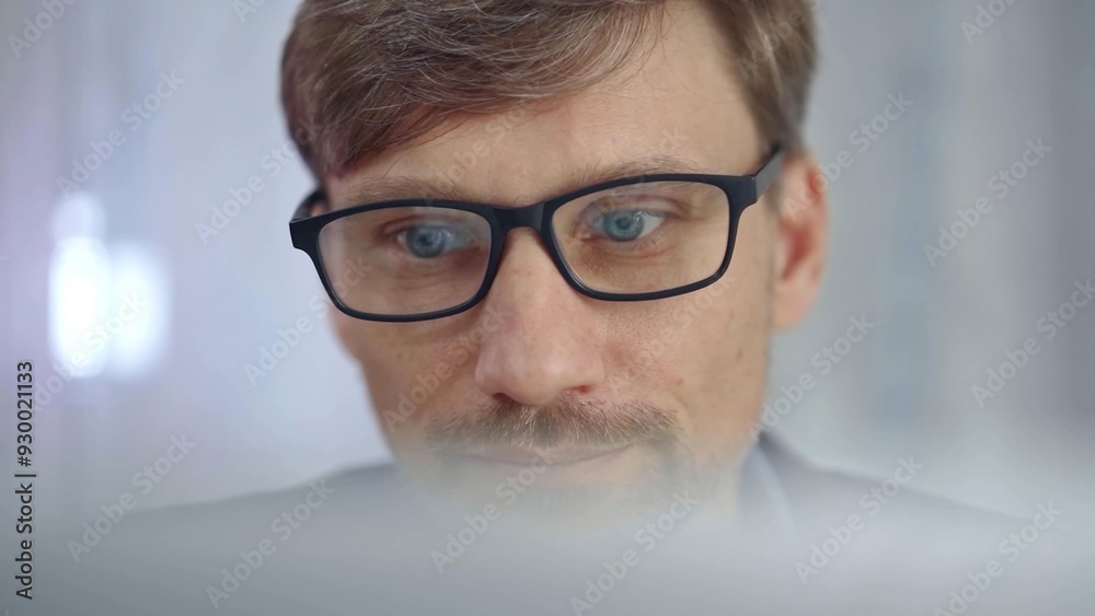 Businessman with glasses looking intently obscured partially by a translucent surface of laptop. Business concept Businessman with glasses looking intently obscured partially by a translucent surface of laptop. Business concept