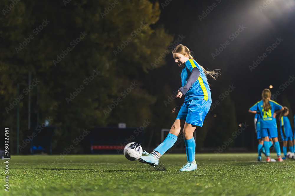 little girl with long hair and blue uniform kicking a ball, practice before the match, footballer girls. High quality photo little girl with long hair and blue uniform kicking a ball, practice before the match, footballer girls. High quality photo
