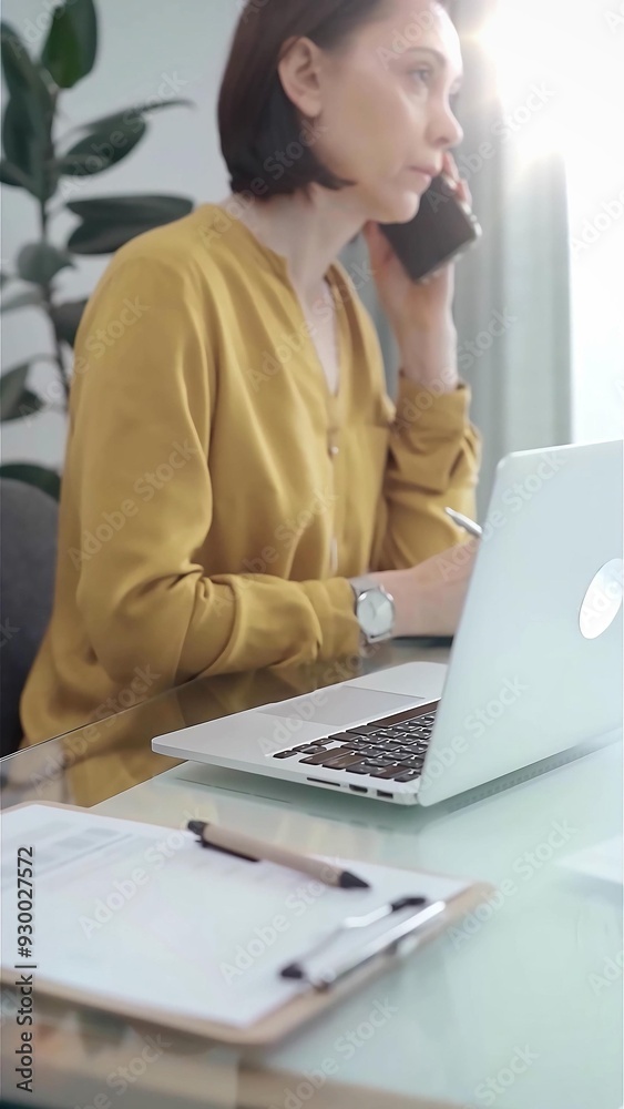 Young professional woman is talking by smartphone in flair office. Yellow blouse is passing to adult businesswoman. Business concept Young professional woman is talking by smartphone in flair office. Yellow blouse is passing to adult businesswoman. Business concept