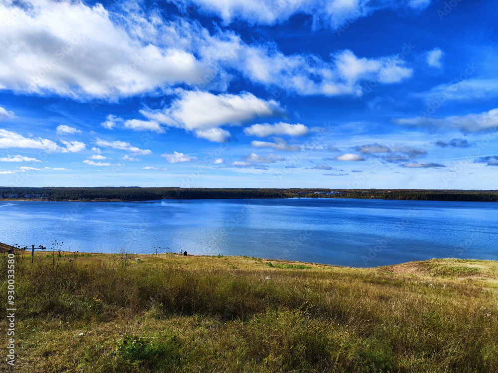 Tranquil lakeside view with grassy hillside under a clear blue sky in the afternoon Tranquil lakeside view with grassy hillside under a clear blue sky in the afternoon