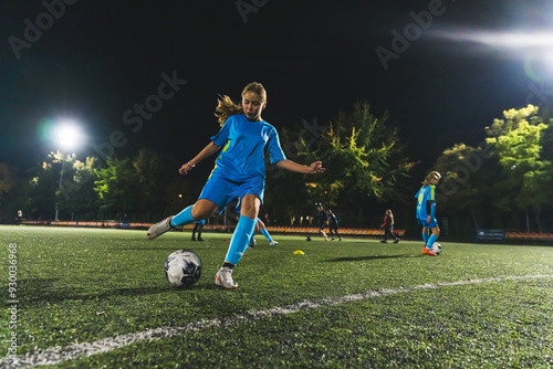 soccer player girl with long hair kicking a ball at a match in the stadium at night. High quality photo