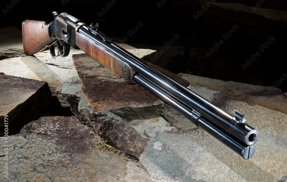 Lever action rifle on stone with a dark background