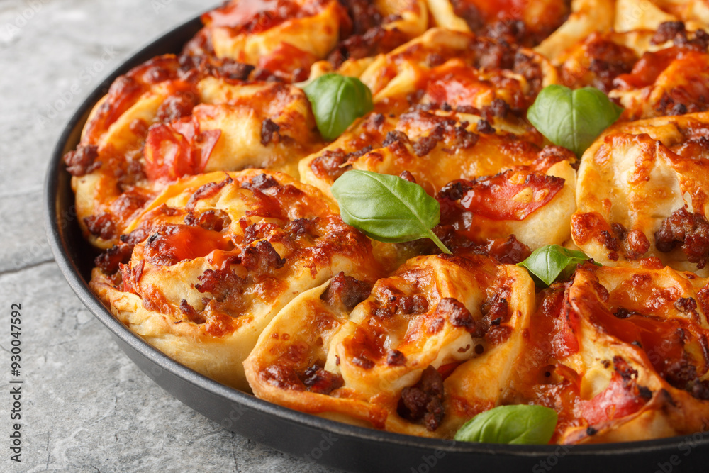 Hot pizza roll with tomatoes, cheese, Italian sausages and basil close-up in baking dish on table. Horizontal Hot pizza roll with tomatoes, cheese, Italian sausages and basil close-up in baking dish on table. Horizontal