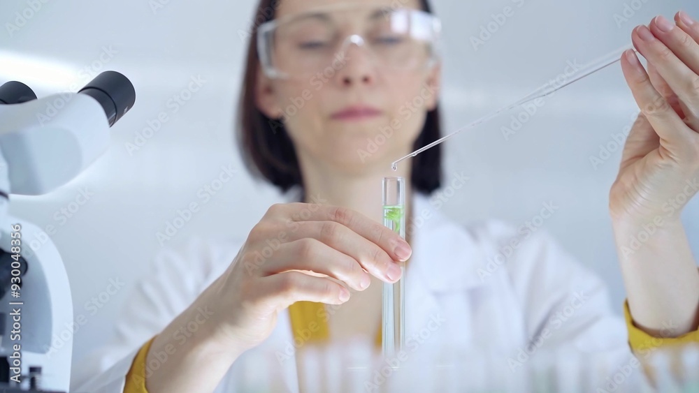Woman with safety glasses is working with lab tubes using a pipette in a modern laboratory, close-up of researcher. Science and medicine Woman with safety glasses is working with lab tubes using a pipette in a modern laboratory, close-up of researcher. Science and medicine