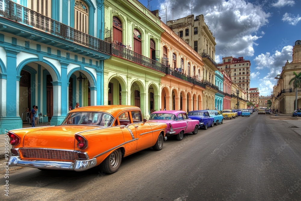 Fototapeta premium Vibrant colonial buildings with vintage cars parked along street, showcasing classic Cuban architecture and automobiles