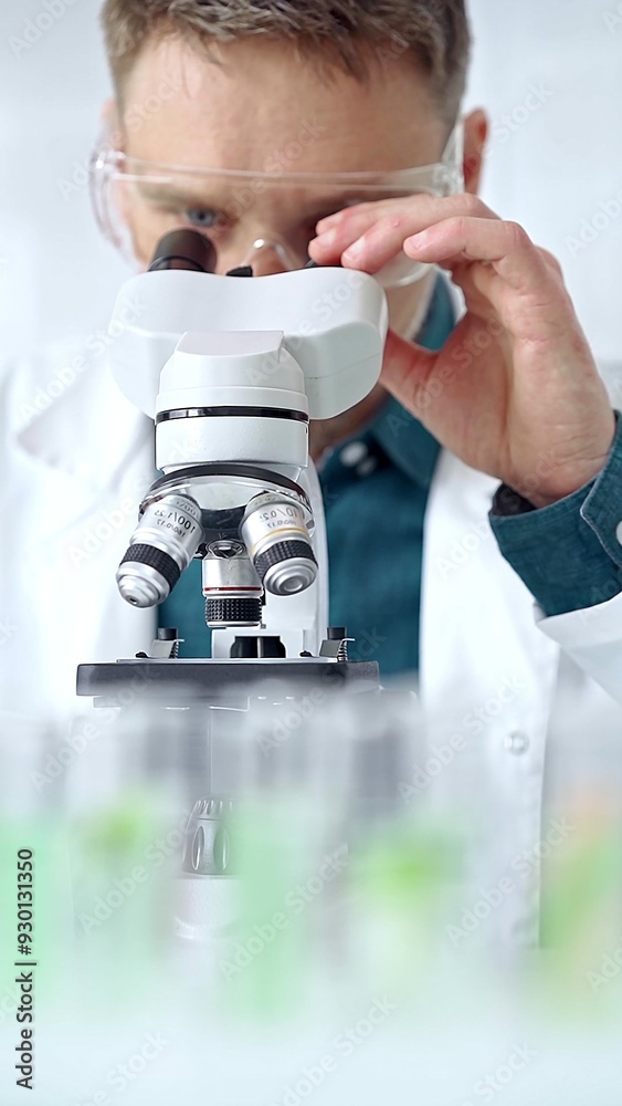 Man scientist with protective glasses using microscope in laboratory. Microbiology science concept Man scientist with protective glasses using microscope in laboratory. Microbiology science concept