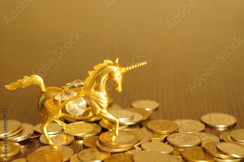 Valokuva A golden unicorn with coins on the table. Finance and economics.