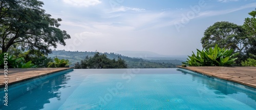  A large swimming pool encircled by lush, green trees Beyond, a clear blue sky, and in the distance, a mountain range