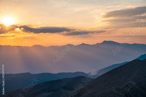 The setting sun over the mountains, the beautiful sun's rays shine through the clouds, the natural background, freedom, tranquility and peace