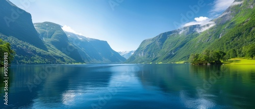  Surrounded by lush green mountains, a large body of water reflects a blue sky dotted with clouds