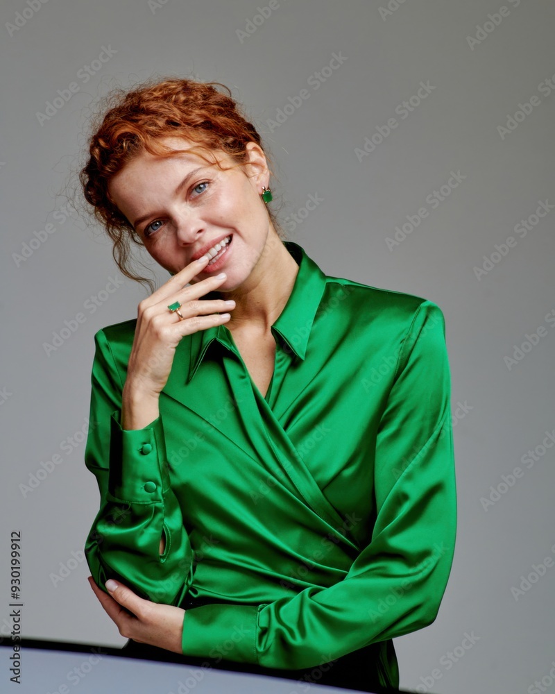 The beautiful red-haired model, dressed in an elegant outfit with jewelry, smiles and radiates joy.