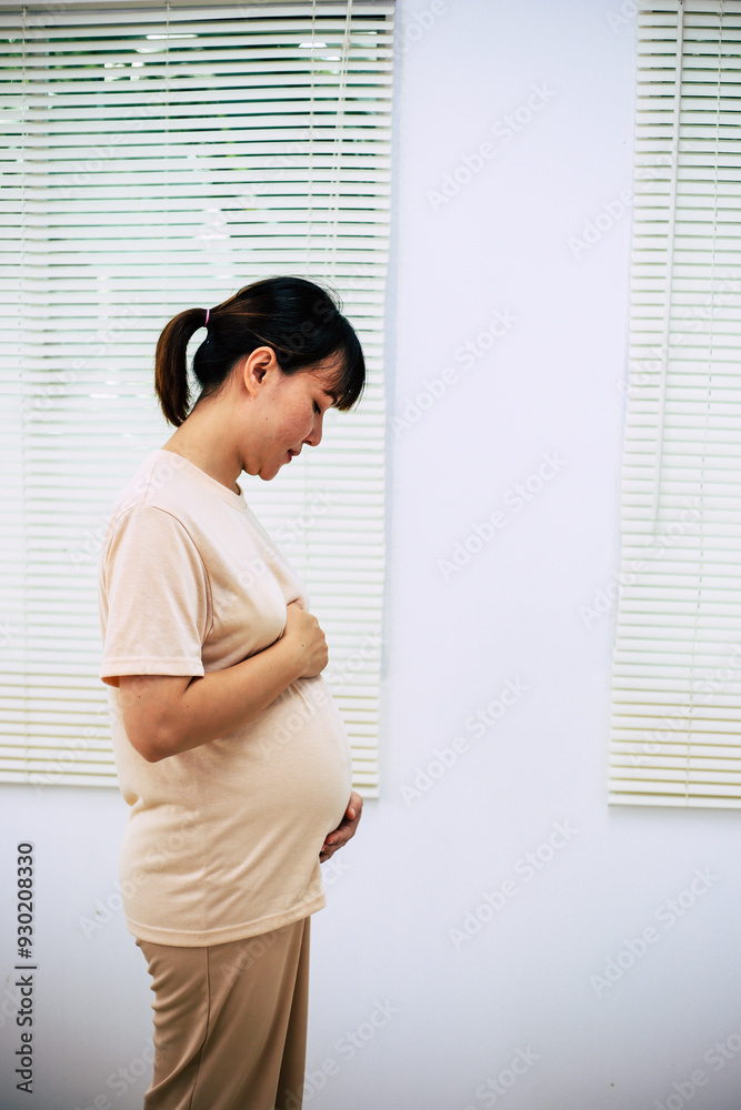 Detail of pregnant woman wearing white clothing and holding her belly with both hands. Detail of pregnant woman wearing white clothing and holding her belly with both hands.